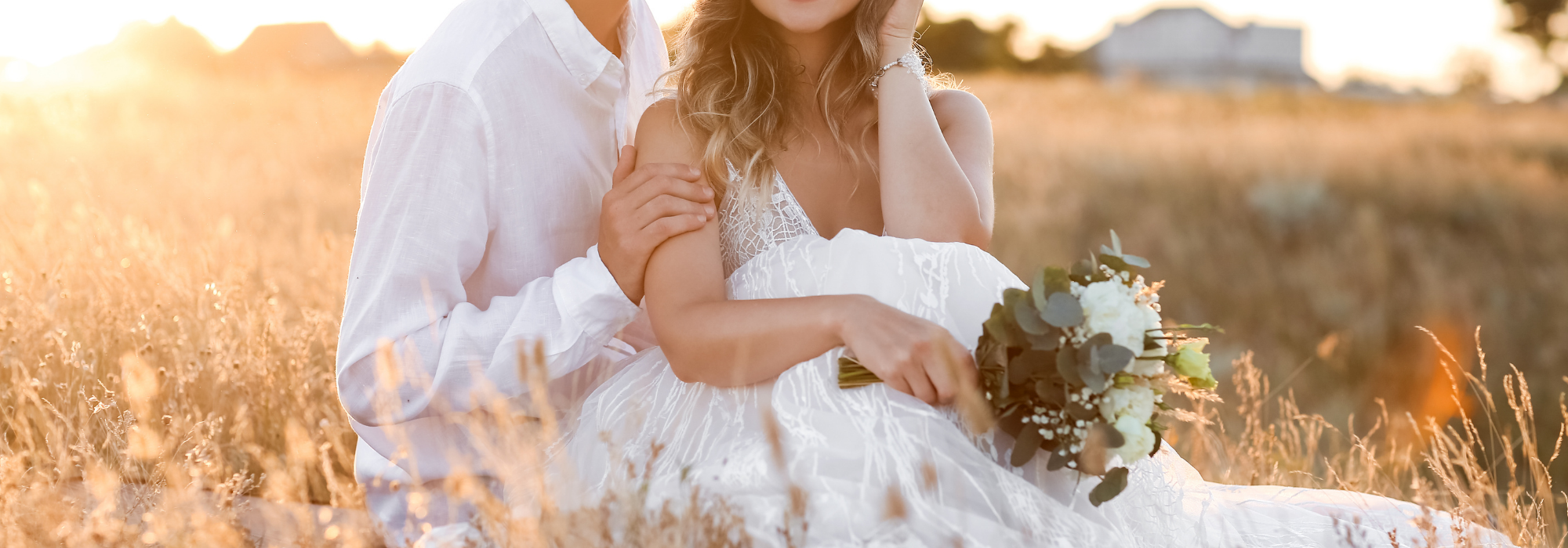newly weds with a bride in a boho dress sitting in an open field 