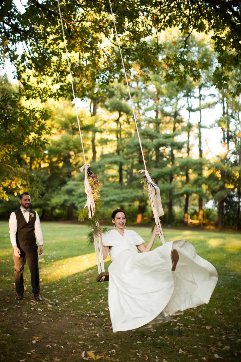 groom pushing bride on rope swing in trees