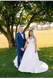 bride and groom posing under tree